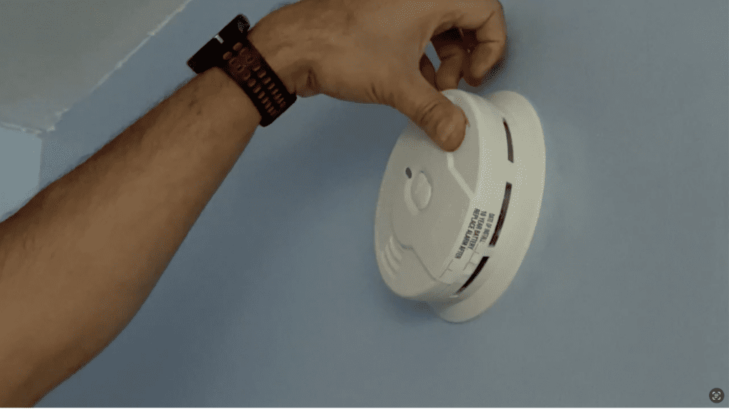 A person testing an installed fire alarm.